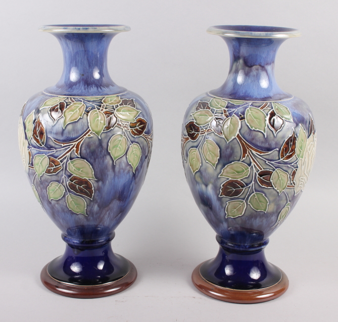 A pair of Royal Doulton blue glazed vases with flared tops and ovoid bodies, tub lined decoration of