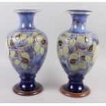 A pair of Royal Doulton blue glazed vases with flared tops and ovoid bodies, tub lined decoration of