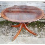 A reproduction mahogany and rosewood banded circular extending dining table with extra leaf, on