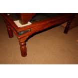 A sheesham and glass topped rectangular coffee table with wrought ironwork decoration, on turned