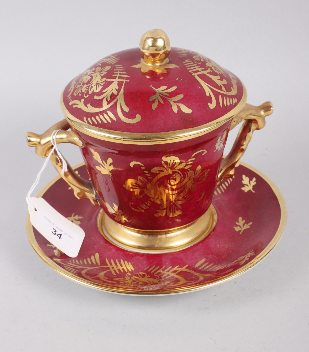 A Limoges two handle cabinet cup, saucer and cover with gilt decoration and crimson ground, 7" high