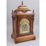 An oak cased mantel clock with brass relief decoration, on brass scrolled supports, 16 1/2" high