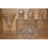 Three cut glass decanters with bulbous stoppers, a cut glass trumpet vase and one other glass vase