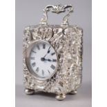 A late Victorian silver cased miniature carriage clock with embossed Rococo decoration, white enamel