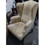 An oak framed wingback armchair, upholstered in a floral fabric (for restoration)