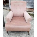 A button back low armchair, upholstered in a pink velour, on turned and castored supports