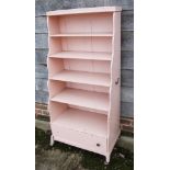 A pink painted five-tier waterfall bookcase, fitted drawer, on castored support, 26" wide x 15" deep