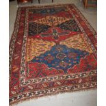 A Middle Eastern rug with tree and flower designs and multi-borders on a red ground in shades of