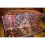 A Kashmir carpet with floral design and central medallion in shades of red and natural on a dark