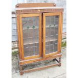 A 1930s oak china cabinet enclosed leaded glazed doors, on turned and stretchered support, 36"