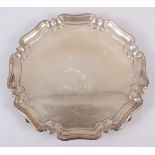 A silver pie crust salver, on three scrolled feet, 16.1oz troy approx