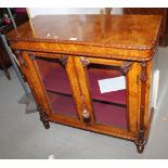 A Victorian burr walnut side cabinet with two glazed doors flanked by turned columns, on turned