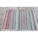A flatweave rug with all-over striped design in shades of green, grey, blue and natural, 54" x 79"
