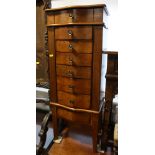 A polished as walnut jewellery cabinet with lift-up lid, fitted seven drawers and fold-out