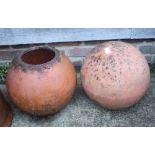 A spherical terracotta planter, 13" high, and a similar terracotta ornamental garden ball