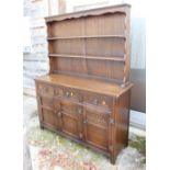 A Jaycee oak dresser with three short drawers above three carved panel doors, on stile supports,