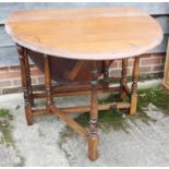 An oak drop leaf table, on turned support, 35" x 61" when fully extended