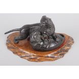 A late 19th century Japanese bronze mode of two tigers fighting, on associated hardwood stand