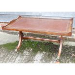 A walnut tray top coffee table with brown leather lining, on splay supports and lion paw castors,