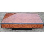 A modern burr walnut and ebonised low coffee table with canted corners, on block base, 47 1/2"