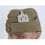 A WWI Kings Own Scottish Borders side cap with badge and buttons upon.