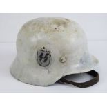 A WWII German SS helmet painted white having green paint under with SS decal upon,