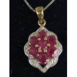 A 9ct gold pendant set with seven oval cut rubies, marked 375, on an 18ct white gold chain. 3.4g.