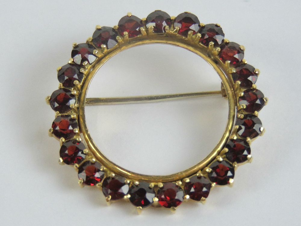 An 18ct gold brooch having twenty-one round cut red stones each approx 3.