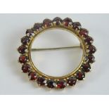 An 18ct gold brooch having twenty-one round cut red stones each approx 3.