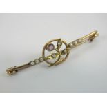 A vintage yellow metal bar brooch having seed pearls and amethyst upon in floral setting,