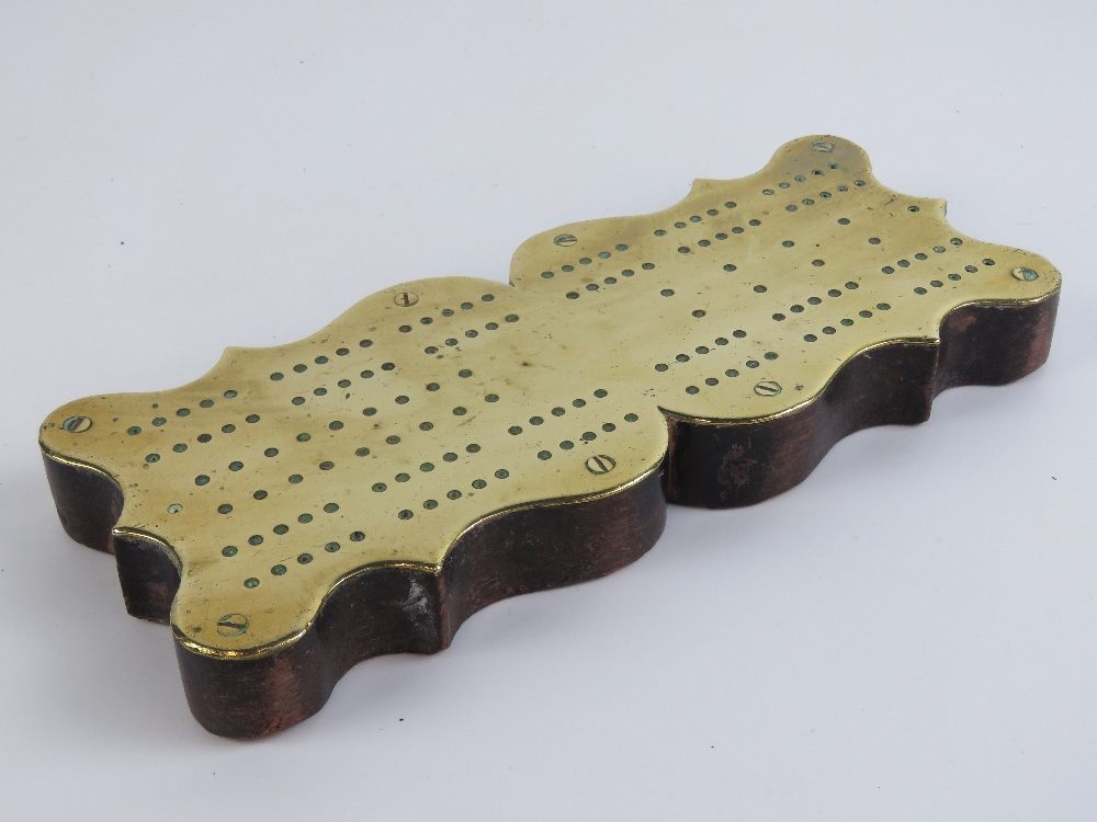A brass cribbage board mounted on shaped mahogany base. 26cm in length.