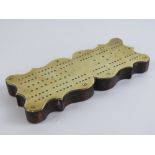 A brass cribbage board mounted on shaped mahogany base. 26cm in length.