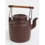 A late 19th / early 20th century Oriental pottery teapot with wooden and wired handle, 11cm dia.