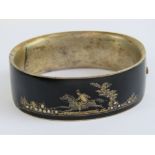 A Victorian black enamel bangle having seed pearl set scene featuring horse and rider,