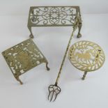 A 20th century pierced brass footman together with two trivets and a toasting fork. Four items.