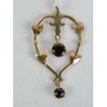 An Edwardian pendant having floral heart shaped frame with two round cut garnets upon,
