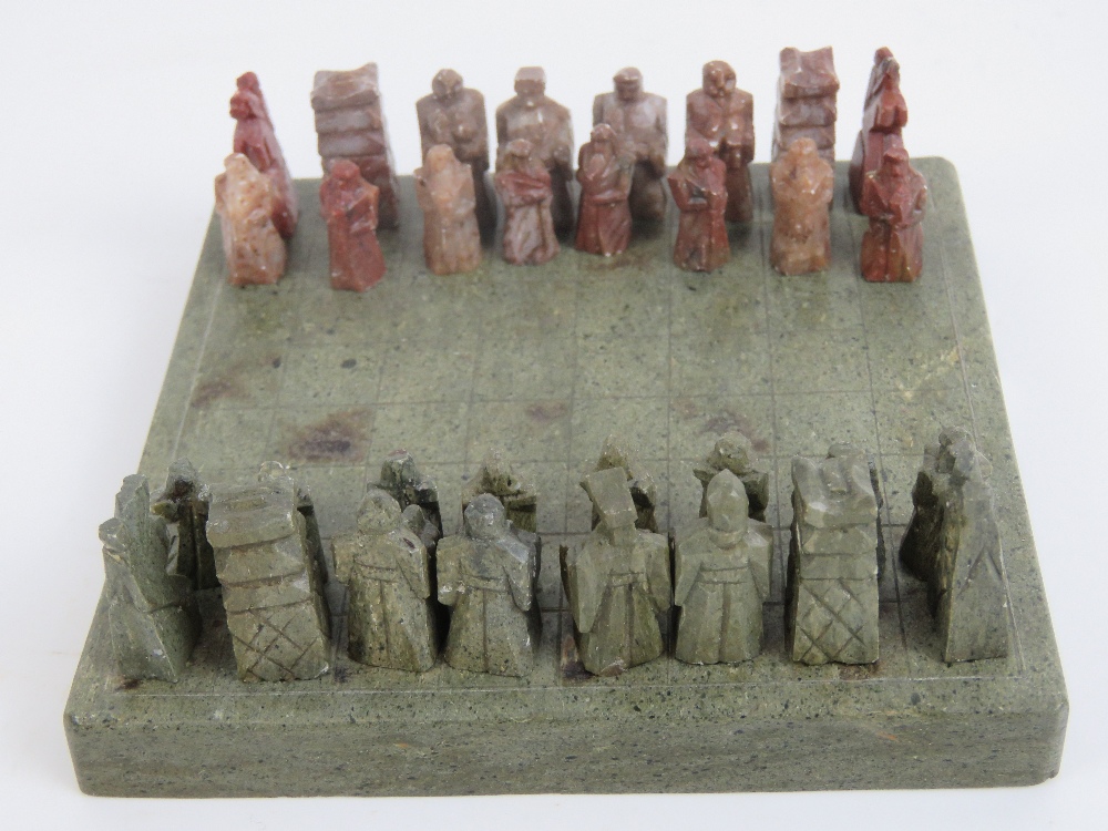 A 20th century Oriental carved stone miniature chess set in case, 10cm square.