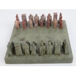 A 20th century Oriental carved stone miniature chess set in case, 10cm square.
