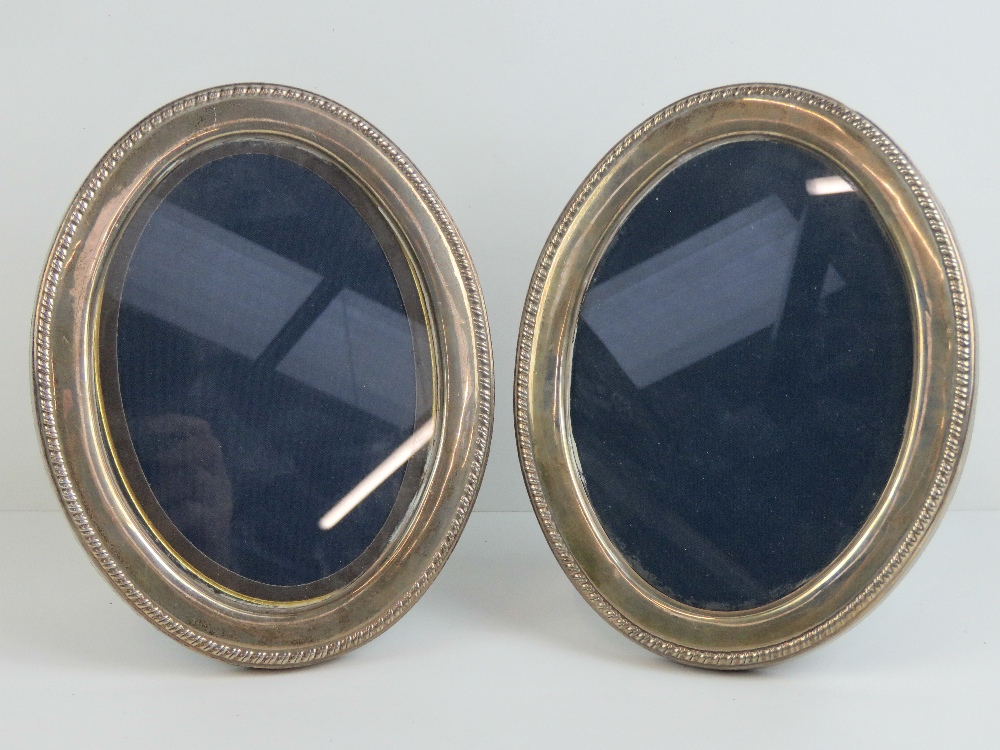 A pair of HM silver oval photograph frames with velvet covered easel backs,