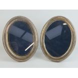A pair of HM silver oval photograph frames with velvet covered easel backs,