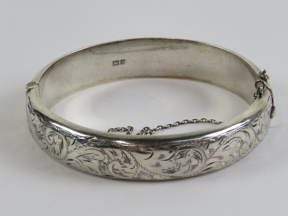 A HM silver hinged bangle having floral engraving to front, hallmarked for Birmingham,