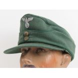 A WWII German Forestry Officers M43 style peaked cap having green piping and eagle over swastika