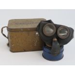 A WWII British variant of child's gas mask with blue filter and carry tin.