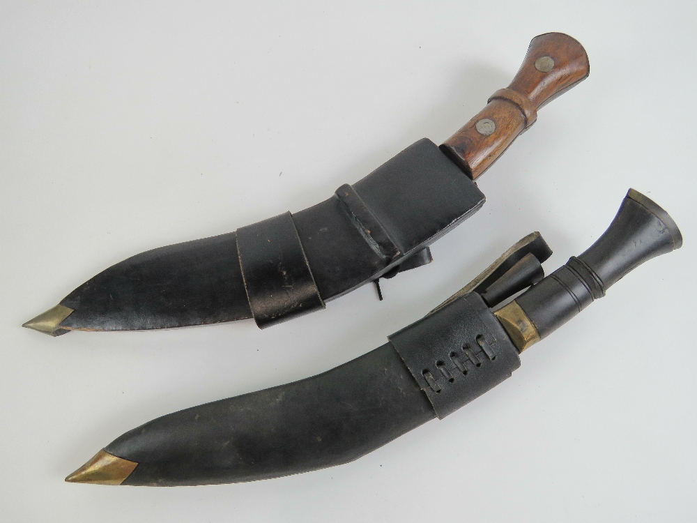 Two Kukris in leather covered wooden sheaths complete with two companion knives in each.