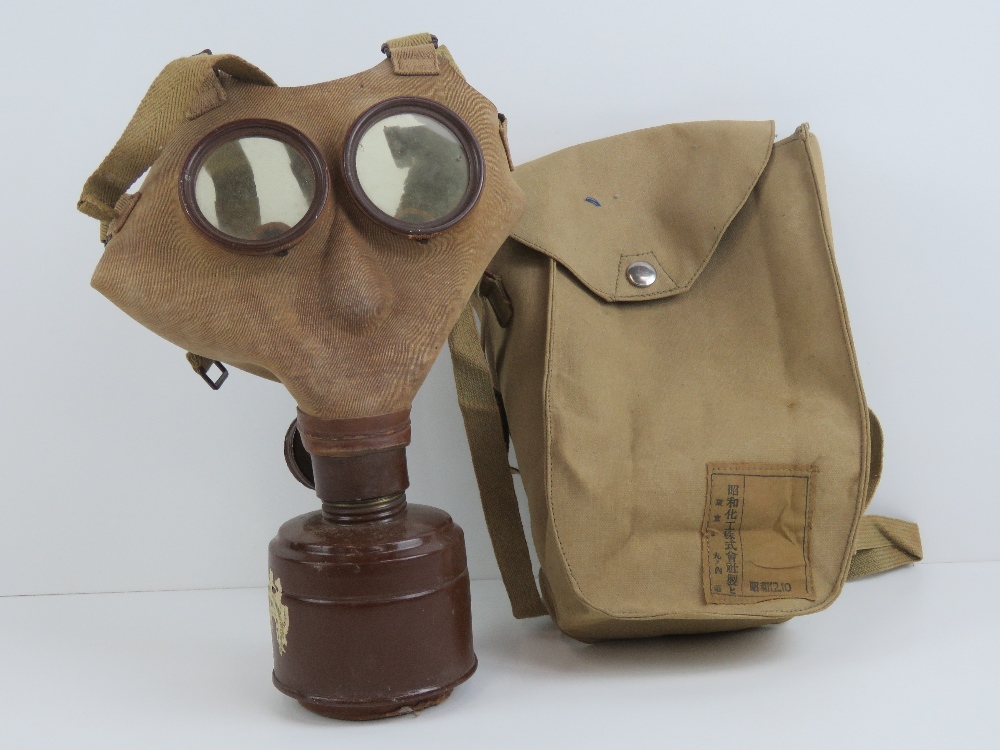 A WWII Japanese civilian gas mask with filter and carry bag with label.