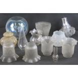 A quantity of assorted vintage glass lamp shades, oil lamp chimneys and a spherical glass bowl.