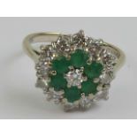 An 18ct white gold diamond and emerald three tier hexagonal cluster ring,