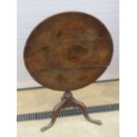 A 19th century circular oak tilt-top table raised over gun barrel stem upon three outswept legs,