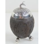An unusual Oriental pepperette formed from a coconut? having peacock design white metal lid and