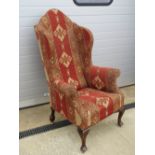 A large and impressive Georgian style wing back open armchair raised over substantial mahogany legs